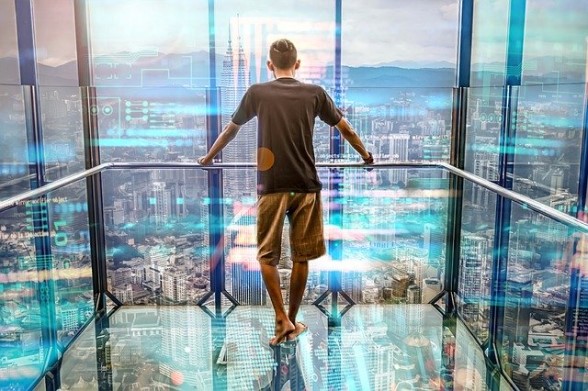 Ragazzo di spalle ammira il panorama dall'interno di un ascensore con le pareti in vetro
